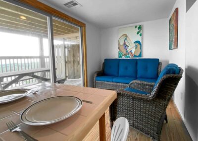 Room 3 - blue love seat in room plus table and view of beach from balcomy doors