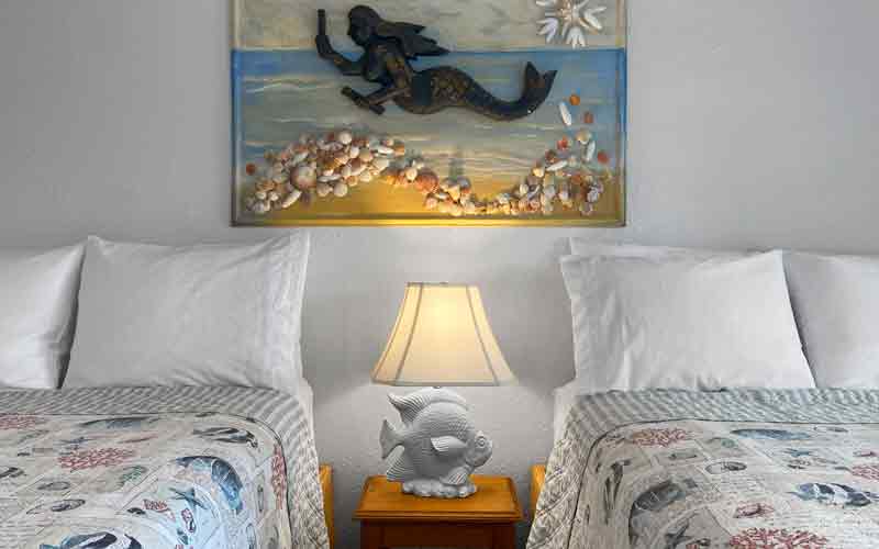 two beds with mermaid mural on wall