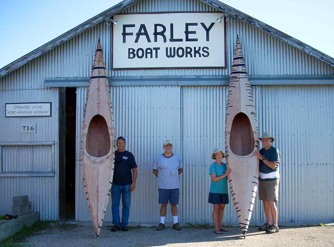 People with kayaks they built, standing in front of Farley Boat Works.