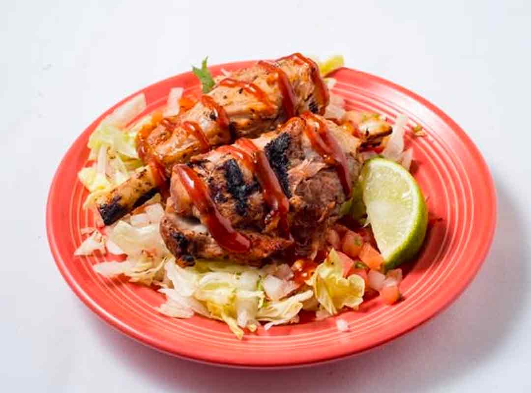 Meat over rice on a red plate at La Playa