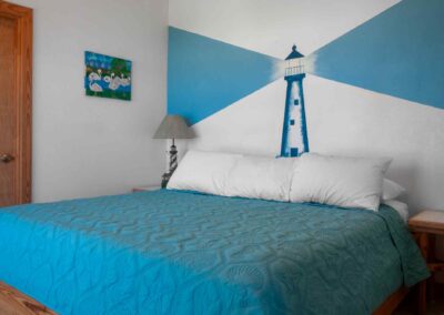 Bedroom in Unit 9, Sandollar Sity Vacation Rentals in Port Aransas, Texas. Painting of lighthouse on wall behind bed.