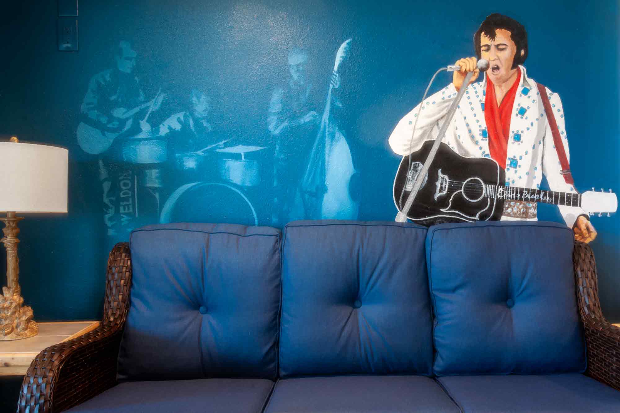 Elvis Presley mural on wall behind sofa