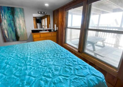 King size bed with turquoise bed spread and window overlooking patio