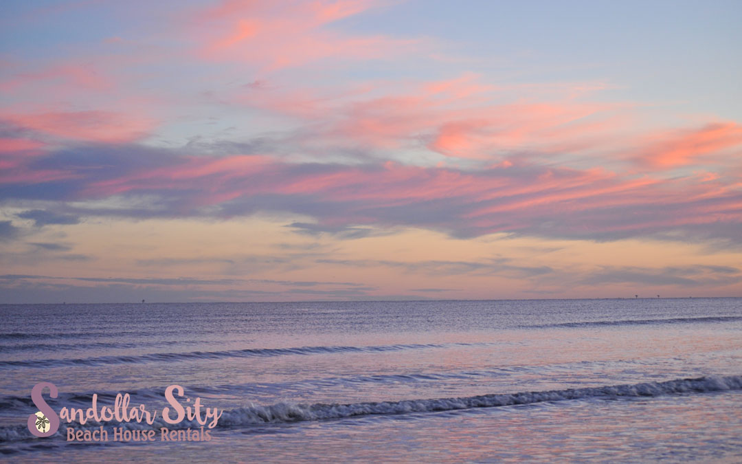 Pink and orange sky reflected in water at the beach in Port Aransas