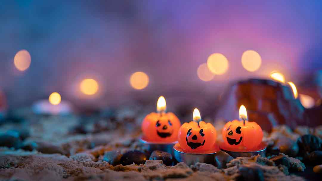 Orange pumpkin candles on a beach