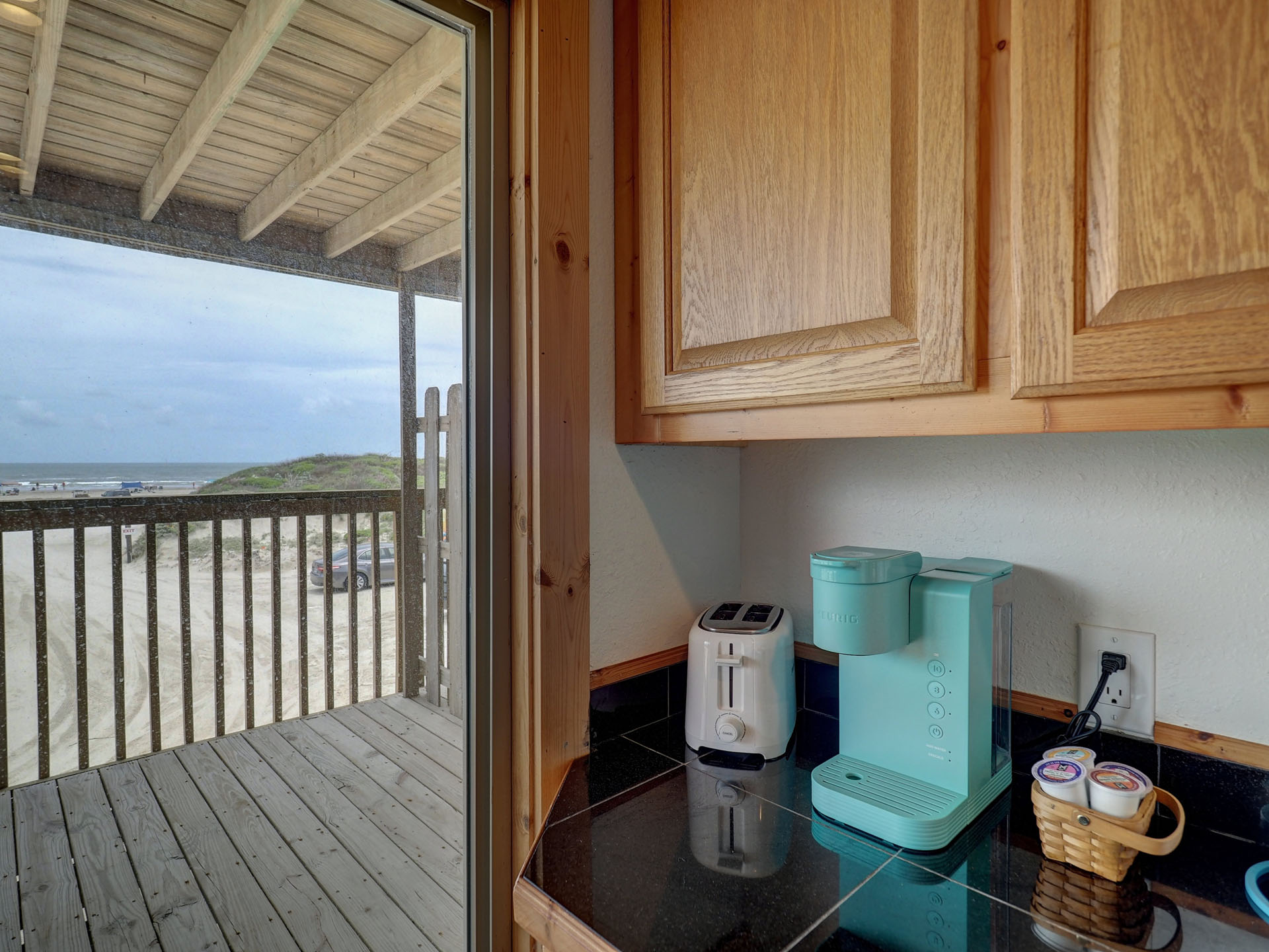 Looking out sliding glass door from kitchen to blue sky and beach